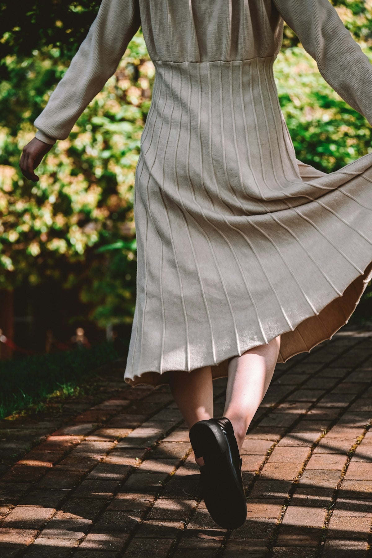 a woman in a dress is walking on a brick path