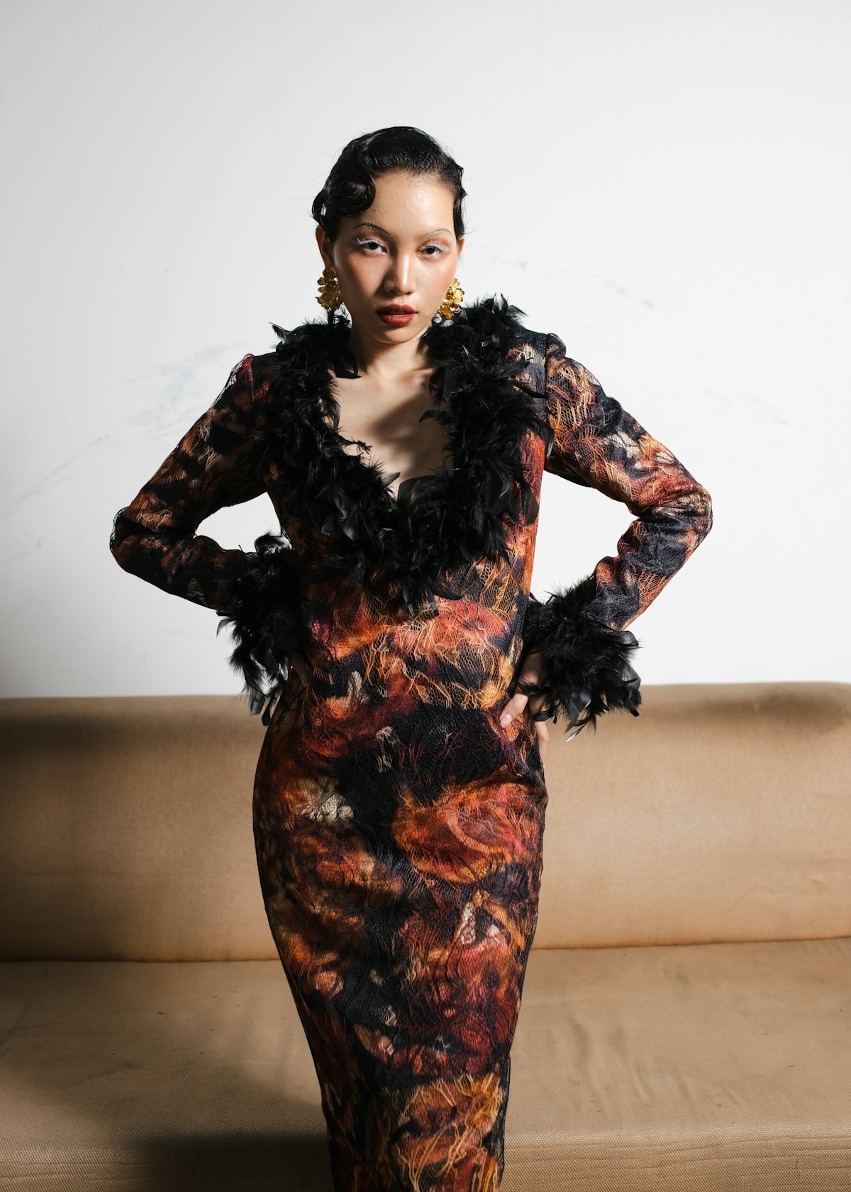 A woman standing in front of a couch wearing a dress