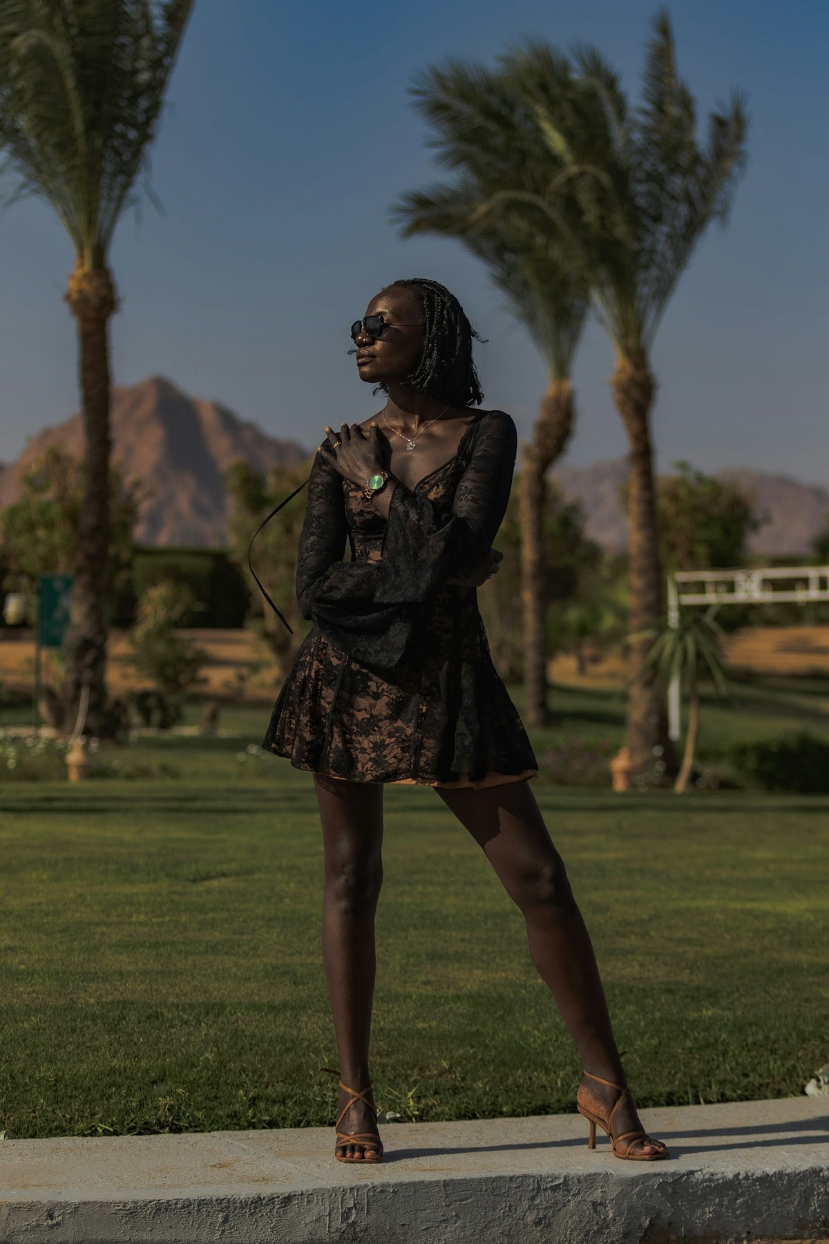 A woman standing on a sidewalk in front of palm trees