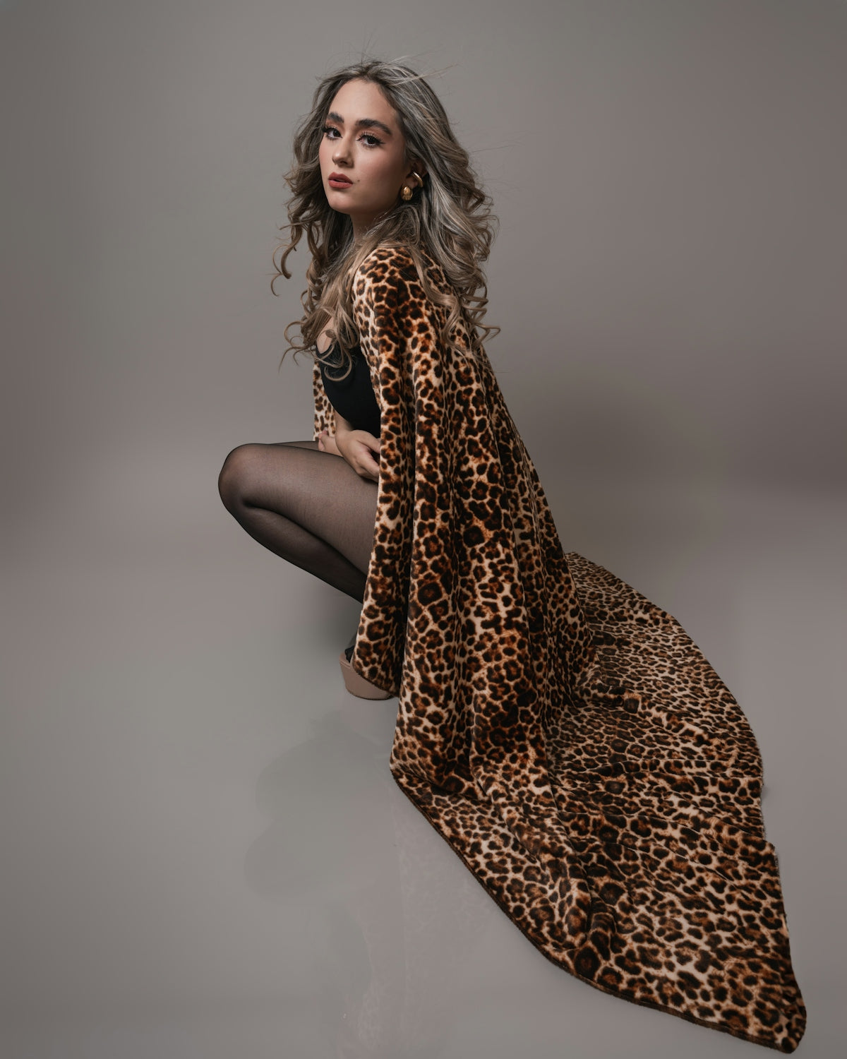 A woman sitting on the ground with a leopard print blanket