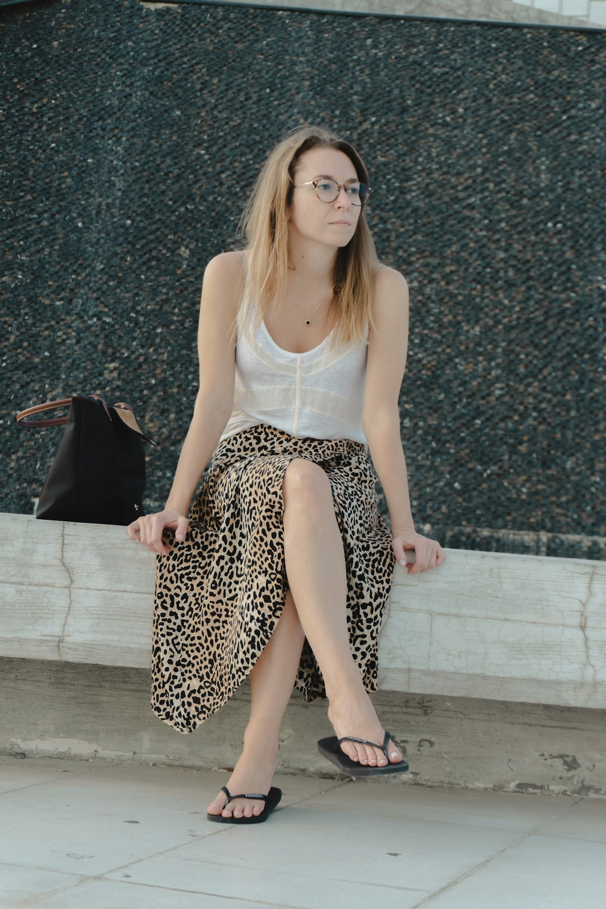 Woman in leopard print skirt sitting outdoors.