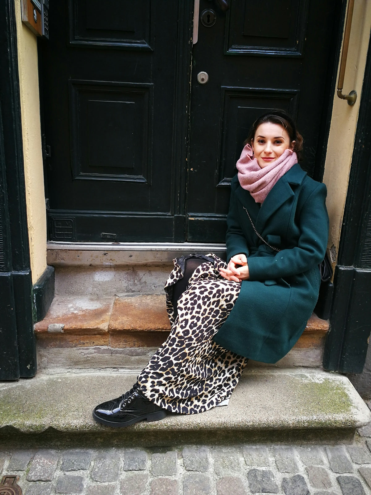 woman in black coat sitting on concrete floor