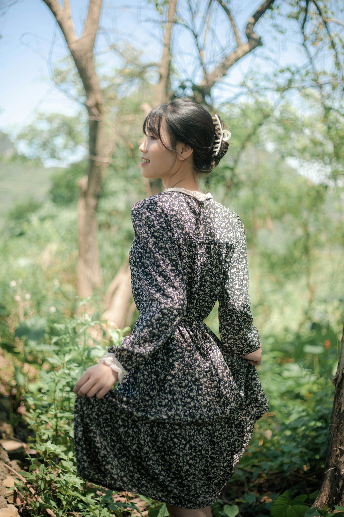 woman in black and white floral long sleeve dress standing on forest during daytime