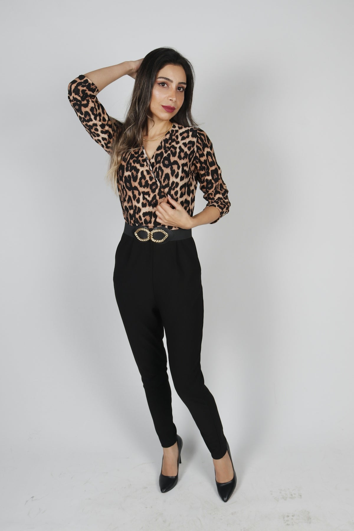 a woman wearing a leopard print shirt and black pants