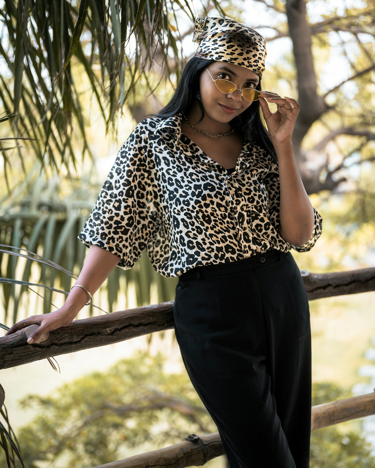 a woman wearing a leopard print shirt and black pants