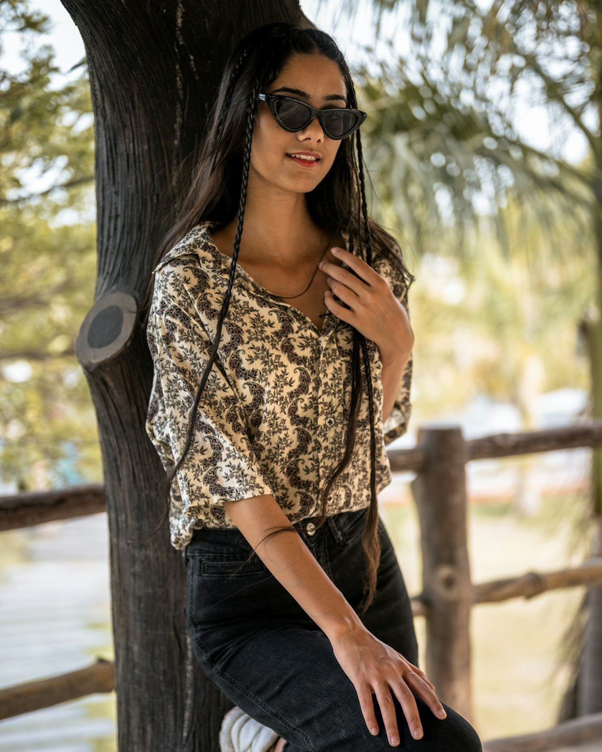 A woman sitting on top of a wooden bench next to a tree
