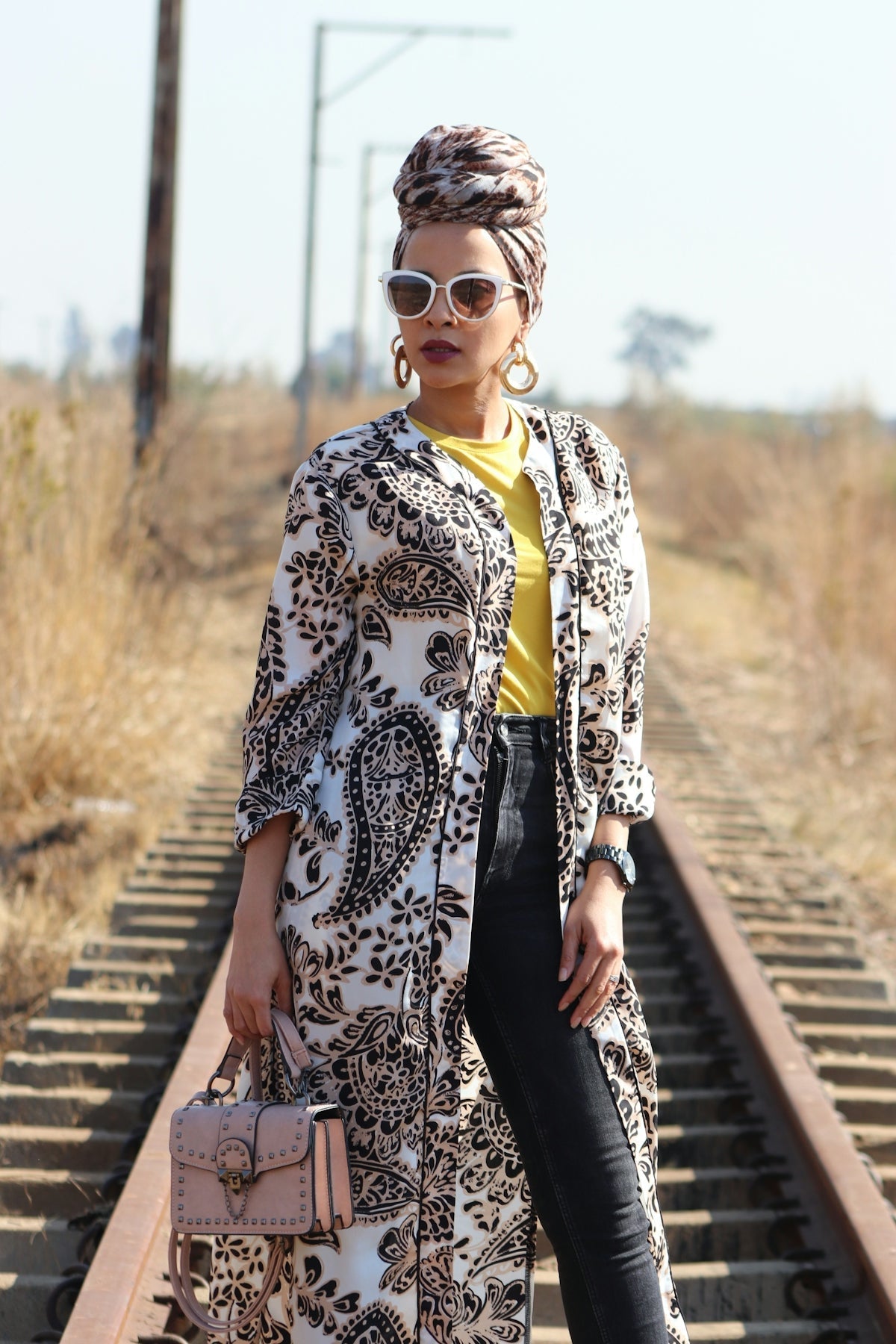 A woman standing on train tracks holding a purse